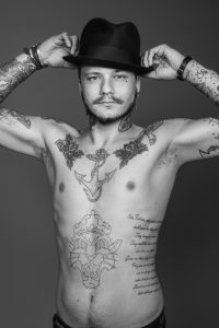 Tatuerare Fredrik Jr håller i hatt, svartvitt