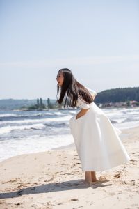 Bruden skrattar och ytter klänning på stranden i Österlen