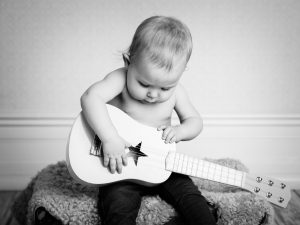 Barnporträtt spelar gitarr i svartvitt