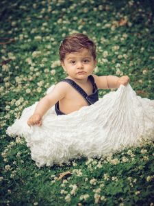 Bebis i parken, sitter i gräset med blommor
