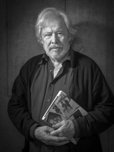 Porträtt på Sven Wollter med bok i svartvitt
